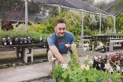 Student sitting behind plant in the nursery